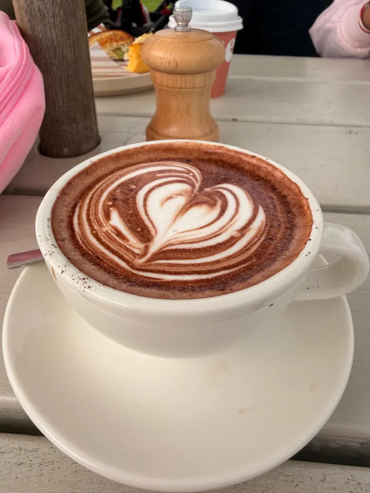 Spiced cacao latte with heart latte art in a cream cup