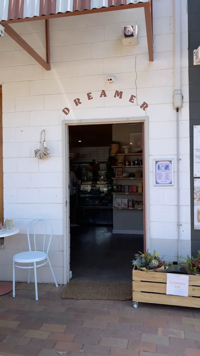 The DREAMER sign arched over the cafe's front door, with a white chair and planter box out front